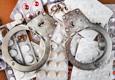 Pills with a Handcuffs on the Brown Paper Background closeup clipart