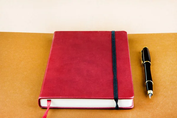 Κόκκινο Βιβλίο Ένα Στυλό Πάνω Closeup Καφέ Χαρτί Υπόβαθρο — Φωτογραφία Αρχείου