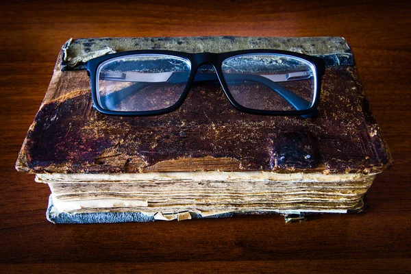 Старая книга с очками — стоковое фото