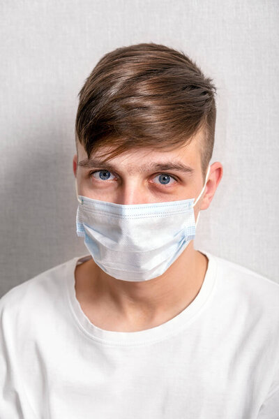 Portrait of Young Man in a Flu Mask by the Wall in the Room