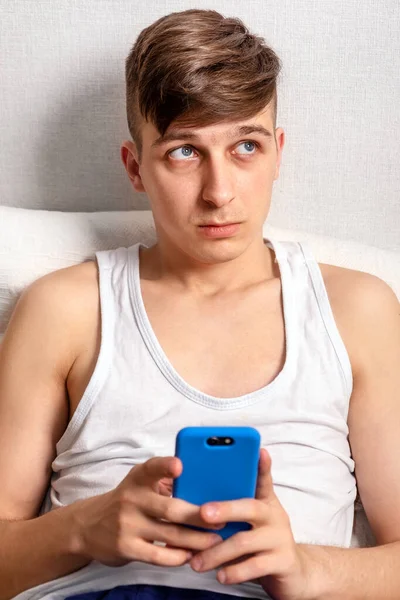 Pensive Mladý Muž Telefonem Sedět Zdi Doma — Stock fotografie