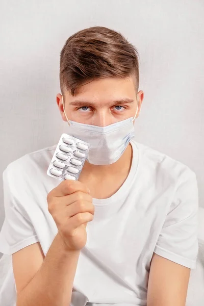 Junger Mann Mit Grippemaske Und Tabletten Der Hand Der Wand — Stockfoto