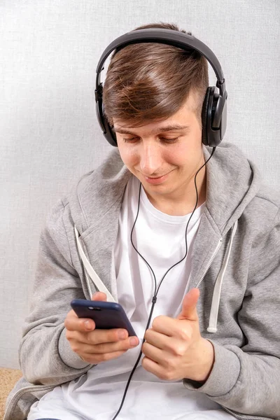 Kulaklıklı Genç Adam Beyaz Duvar Telefon Kullanıyor — Stok fotoğraf