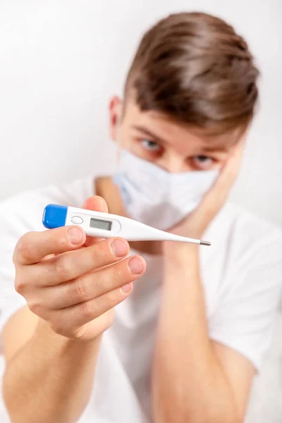 Jongeman Een Griepmasker Toont Een Thermometer Bij Muur Kamer — Stockfoto