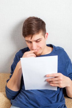 Üzgün genç adam evdeki koltukta bir belge okudu.
