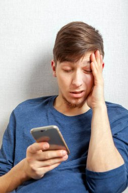Evinin duvarında telefonu olan mutsuz genç adam.