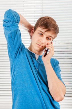 Genç adam, bekle. Bir odada, Jalousie 'nin arka planında bir telefona cevap ver.