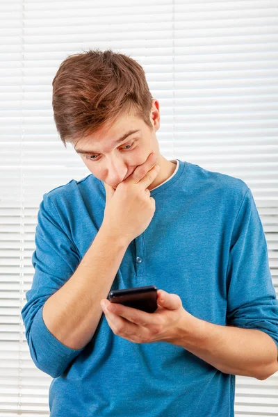 Jovem Problemático Com Telefone Celular Está Pensando Fundo Jalousie Uma — Fotografia de Stock