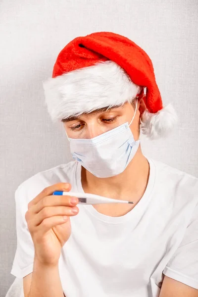 Sick Young Man Santa Hat Και Μάσκα Γρίπης Θερμόμετρο — Φωτογραφία Αρχείου