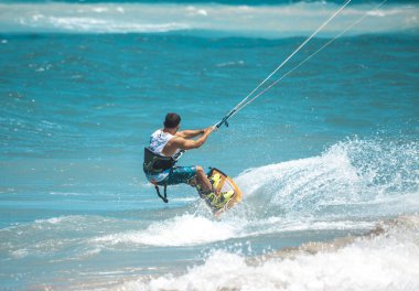 Kitesurfing. Gemide dalga deniz üzerinde uçan genç adam