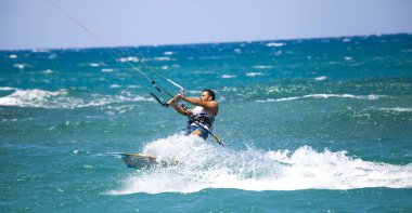 Kitesurfing. Gemide dalga deniz üzerinde uçan genç adam