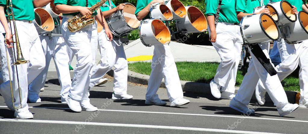 Marching band in uniform performing in a parade outdoors.