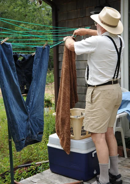 裏庭で洗濯物を洗い干す男性シニア — ストック写真