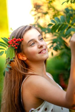 Uzun saçlı bir kızın portresi. Saçında Rowan 'ın resmi var.