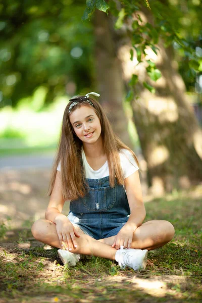 Mooi Tiener Meisje Denim Overalls Zit Het Gras Verlicht Door — Stockfoto