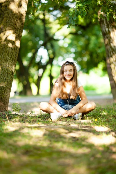 Teenager Mädchen Jeans Overalls Sitzt Auf Dem Gras Beleuchtet Von — Stockfoto