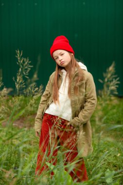 Bulanık bitki arka planında sıradan sonbahar elbiseleri giyen bir kız.