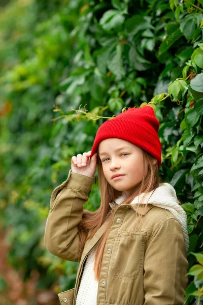 背景色の悪い植物の背景に普通の秋の服の女の子 — ストック写真