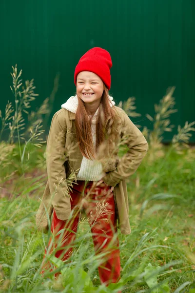 背景色の悪い植物の背景に普通の秋の服の女の子 — ストック写真