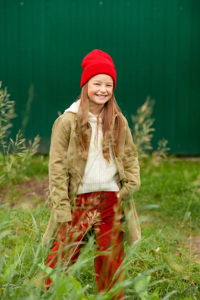 背景色の悪い植物の背景に普通の秋の服の女の子 — ストック写真