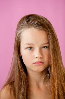 9 yaşındaki zarif, uzun saçlı bir kızın eflatun bir duvara dayanmış portresi.