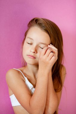 9 yaşındaki zarif, uzun saçlı bir kızın eflatun bir duvara dayanmış portresi.