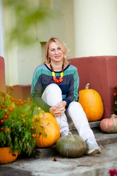 mature calm woman on the porch of a house with columns in autumn