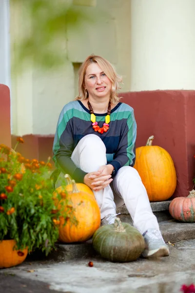 mature calm woman on the porch of a house with columns in autumn