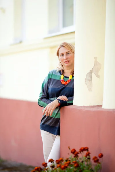 mature calm woman on the porch of a house with columns in autumn