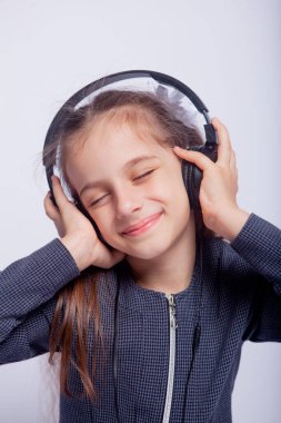 Katı okul kıyafetleri içinde açık gri arka planda bir kızın portresi.