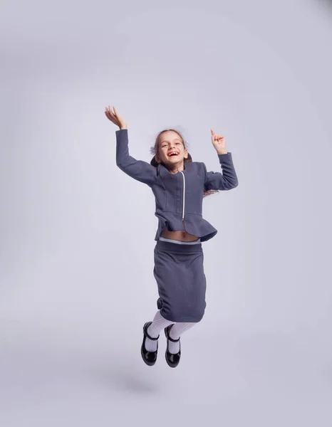 Retrato Menina Saltando Roupas Estritas Escola Fundo Cinza Claro — Fotografia de Stock