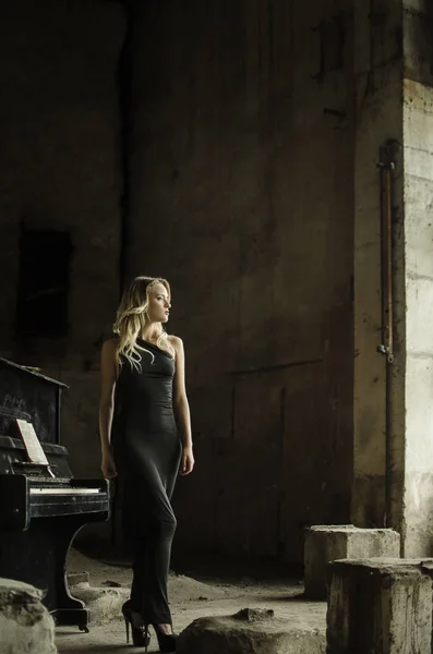 在钢琴附近的粗野工作室的照片中摆姿势的女孩 — 图库照片