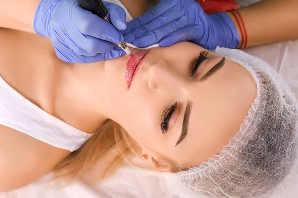 Cosmetologist making permanent makeup on womans lips — Stock Photo, Image