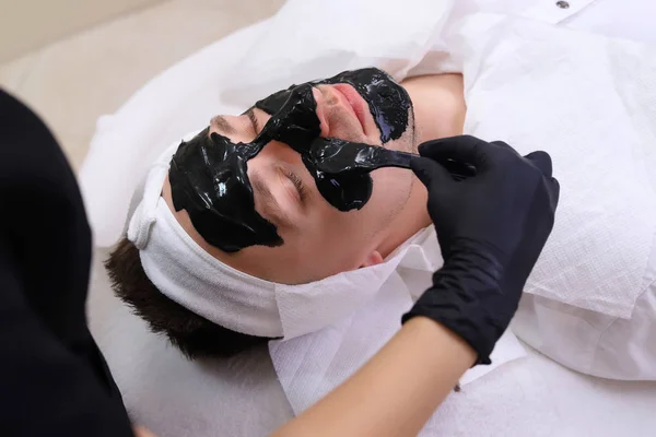 Spa θεραπεία για τους άνδρες που λαμβάνουν μαύρη μάσκα προσώπου. — Φωτογραφία Αρχείου
