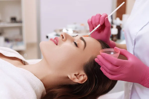 Jonge vrouw schoonmaken gezichtshuid in salon. — Stockfoto