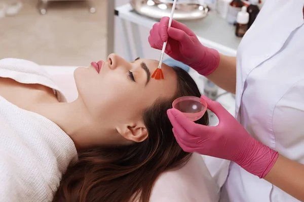 Jonge vrouw schoonmaken gezichtshuid in salon. — Stockfoto