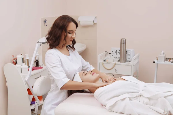 Masaje facial de una mujer joven recibiendo tratamiento de spa . —  Fotos de Stock