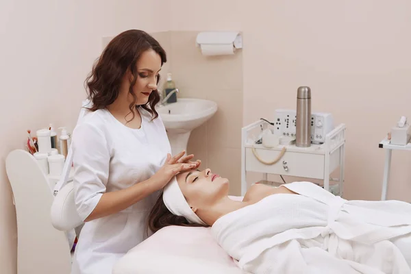 Masaje facial de una mujer joven recibiendo tratamiento de spa . — Foto de Stock