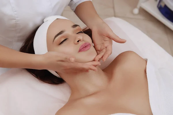 Masaje facial de una mujer joven recibiendo tratamiento de spa . — Foto de Stock