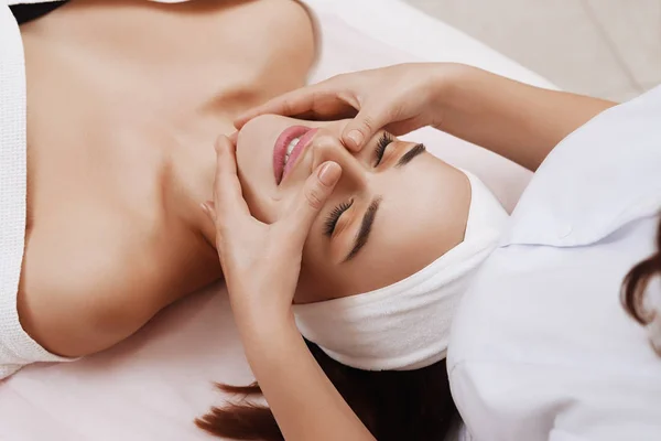 Masaje facial de una mujer joven recibiendo tratamiento de spa . — Foto de Stock