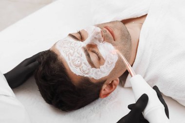 Güzellik kliniği müşterisinin yüzü. Darsonval tedavisi gören adam.