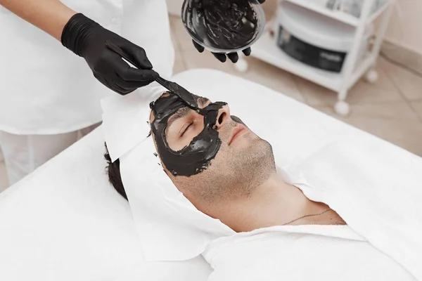 Spa θεραπεία για τους άνδρες που λαμβάνουν μαύρη μάσκα προσώπου. — Φωτογραφία Αρχείου