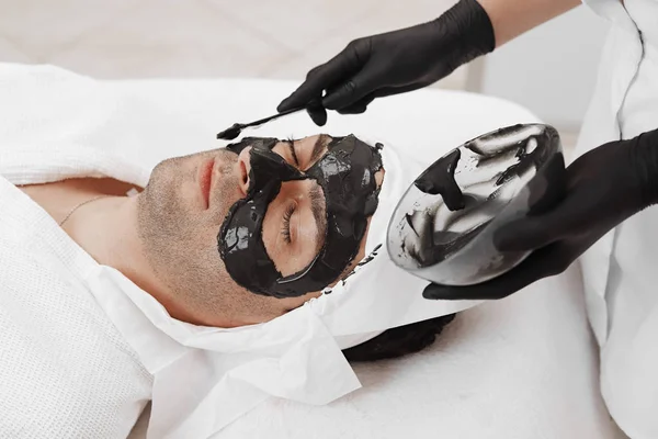 남자 얼굴 검은 마스크를 받기 위한 스파 치료. — 스톡 사진