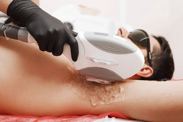 Terapeut dávat laserové epilace ošetření na mladíka v lázních — Stock fotografie