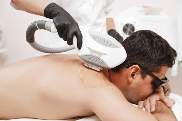 Terapeuta dando tratamento de compilação a laser para o homem jovem no spa — Fotografia de Stock