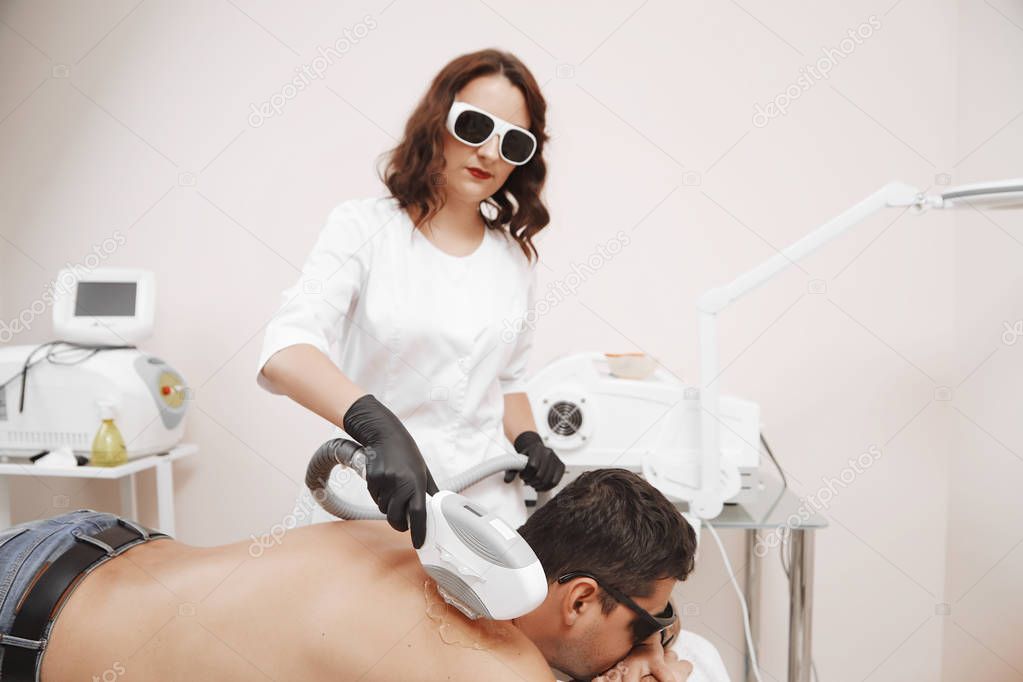 Therapist Giving Laser Epilation Treatment To Young Man In Spa