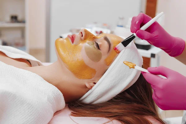 Spa Woman applying Facial cleansing Mask.