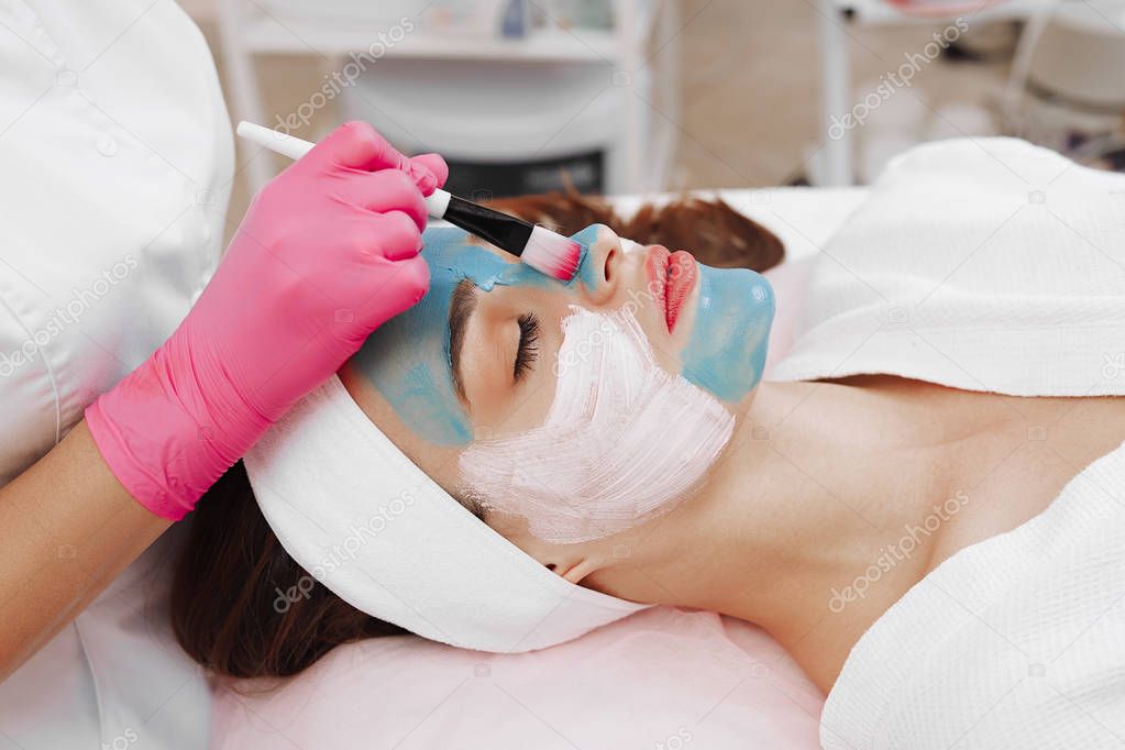 Spa Woman applying Facial cleansing Mask.