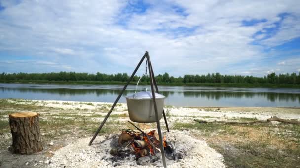 川の近くの暖炉のコールドロンの撮影 — ストック動画