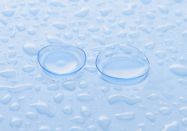 滴の水で覆われた青い表面にアイ コンタクト レンズ — ストック写真